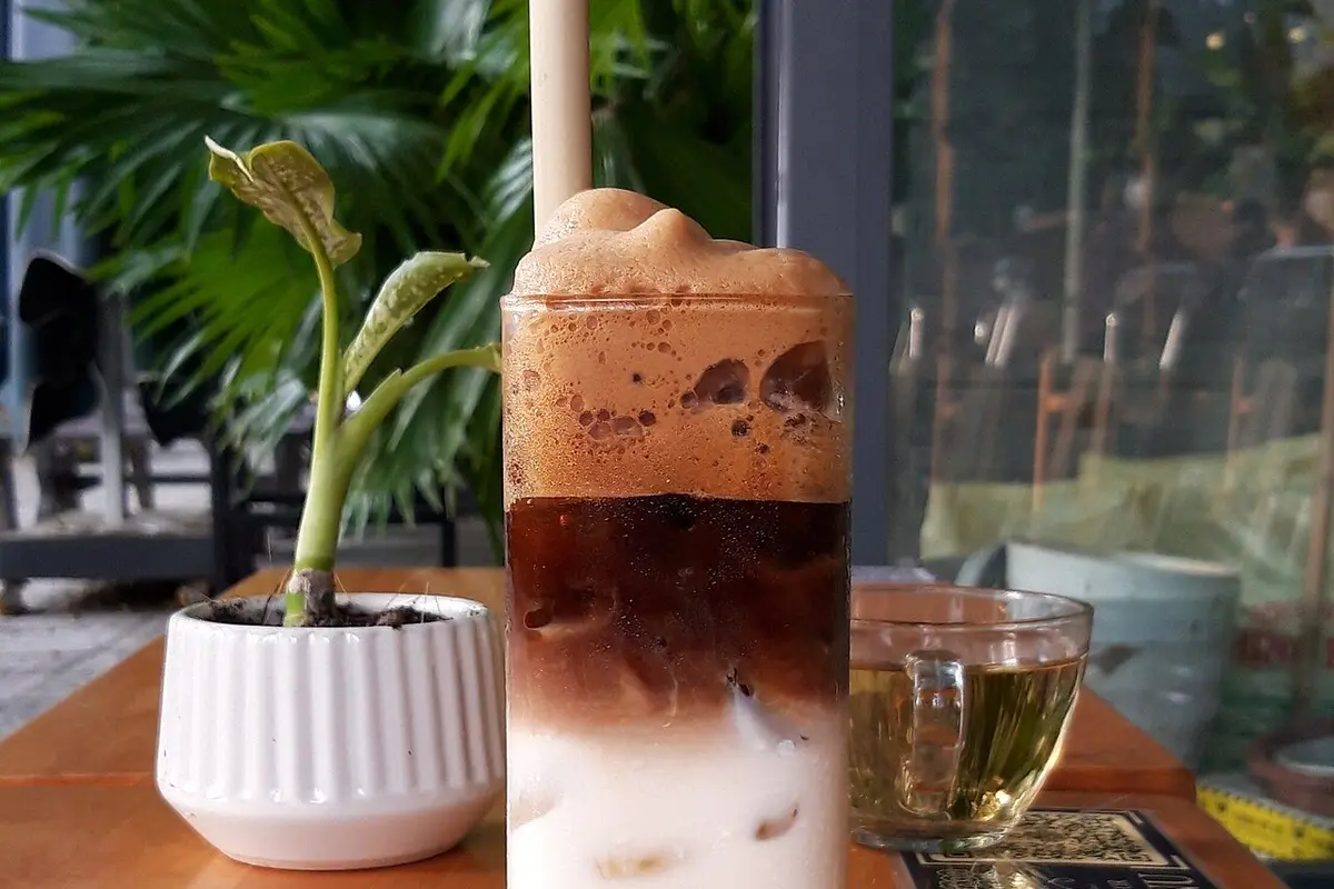 Vaso alto de café frío con hielo y espuma de leche