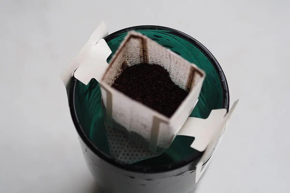 Café de filtro en bolsa goteando sobre la taza
