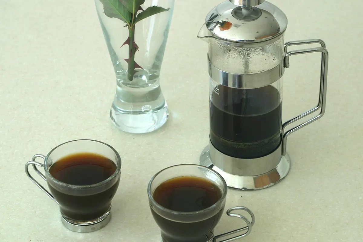 Prensa francesa junto a dos tazas de espresso