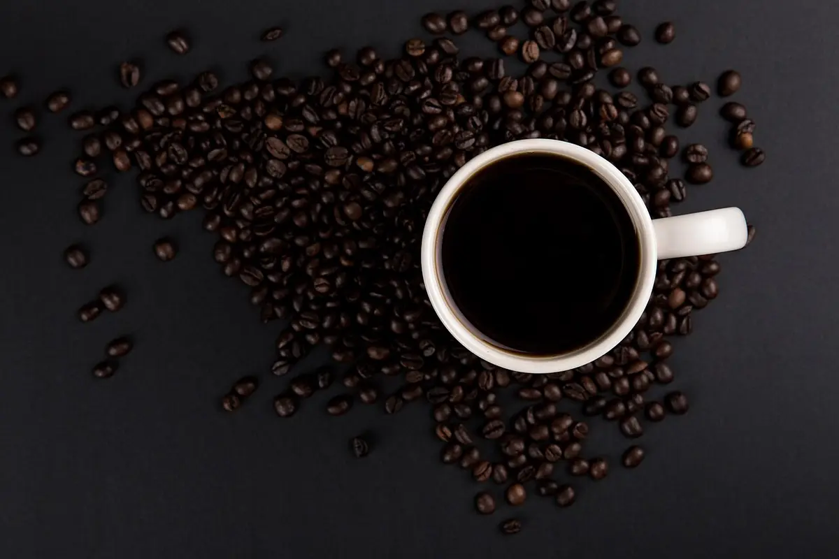 Taza de café rodeada de granos tostados